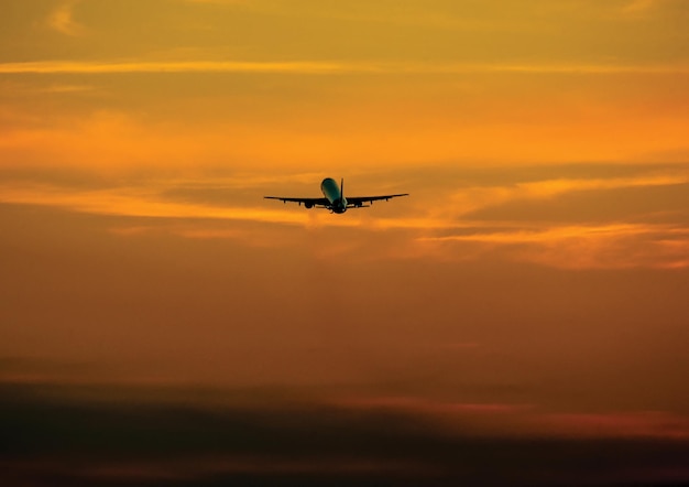Un avion en silhouette volant contre un ciel spectaculaire au coucher du soleil
