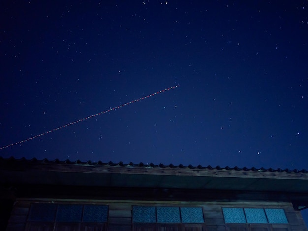 Un avion survole un bâtiment avec des étoiles dans le ciel.