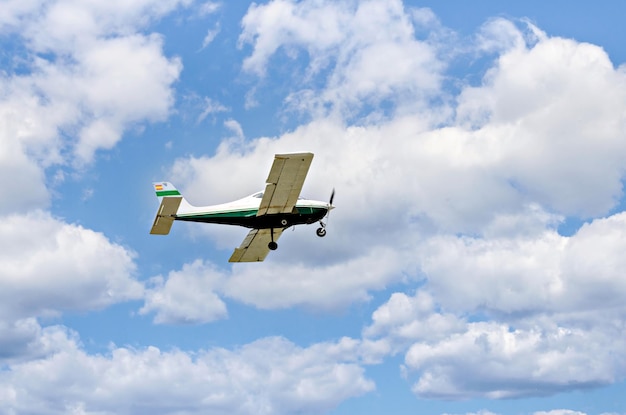 Avion ultra-léger monomoteur volant dans le ciel bleu avec des nuages blancs.