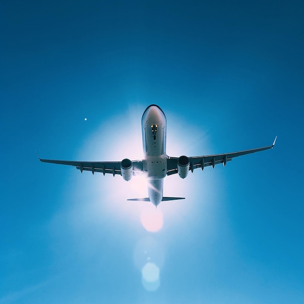 Un avion volant dans le ciel avec le soleil qui brille à travers les nuages.