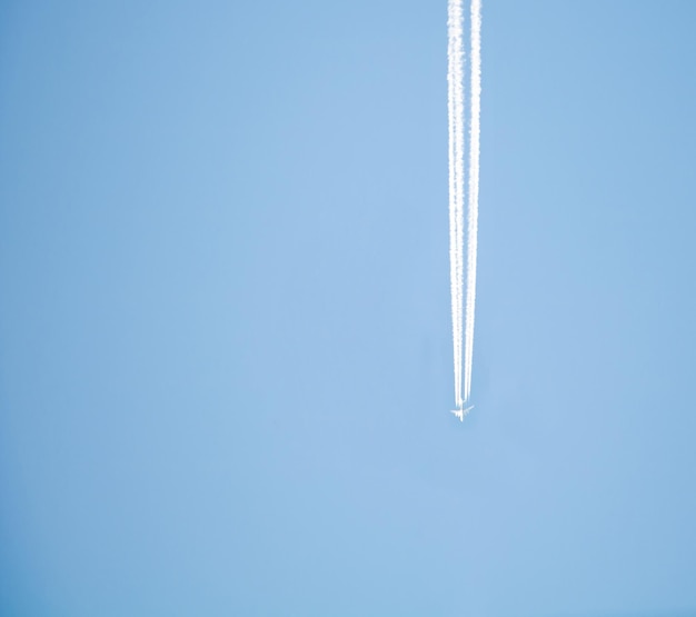 Un avion vole dans le ciel bleu à haute altitude et laisse une ligne blanche derrière