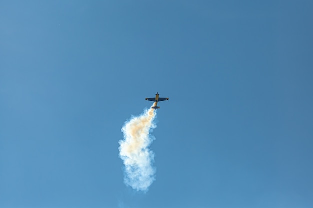 L'avion de voltige avec piste de fumée dans le ciel