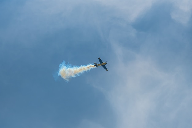 L'avion de voltige avec piste de fumée dans le ciel