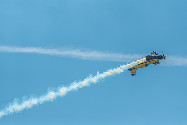 L'avion de voltige avec piste de fumée dans le ciel