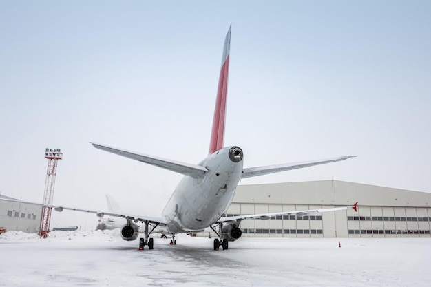 Avions de passagers blancs près du hangar d'aviation par temps froid d'hiver