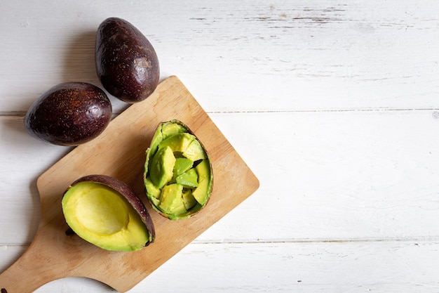 Avocat bio frais coupé en deux sur une table en bois blanc