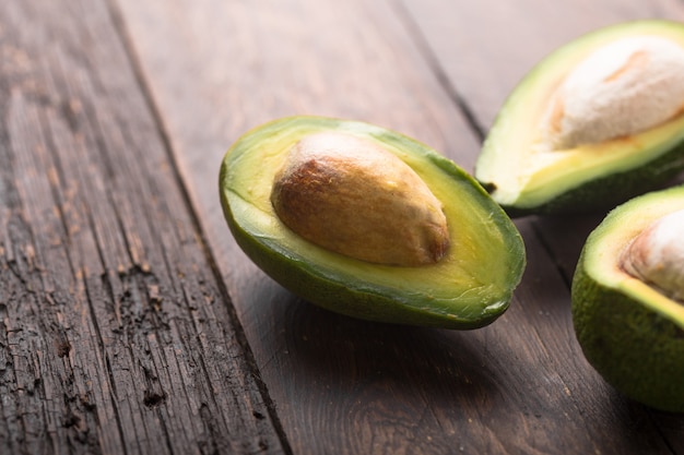 Avocat bio frais, moitiés sur une vieille table en bois