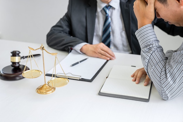 Un avocat ou un conseiller travaillant dans la salle d'audience a une réunion avec le client et consulte les documents contractuels du concept de services immobiliers, de droit et de services juridiques.