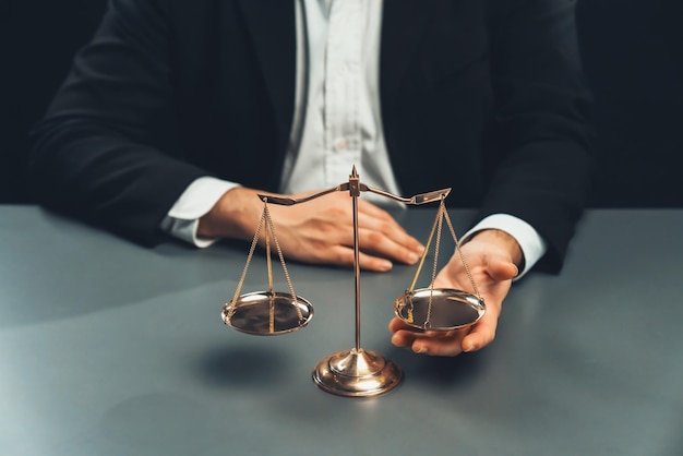 Avocat en costume noir avec balance d'or en équité de bureau