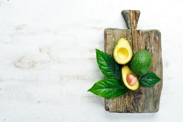 Avocat et feuilles vertes sur un fond en bois blanc Style rustique Vue de dessus Espace libre pour votre texte