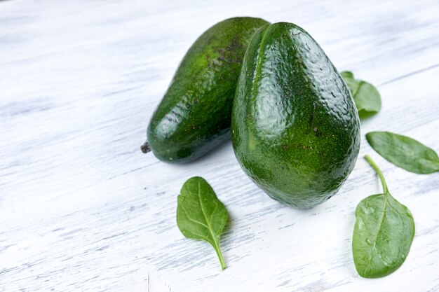 Avocat sur un fond en bois blanc avec des feuilles vertes