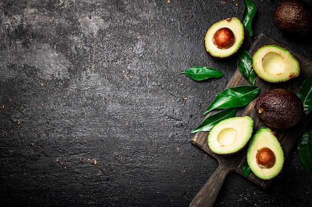 Avocat frais avec feuillage sur une planche à découper