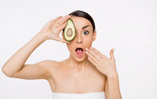 Avocat frais et savoureux Une belle jeune femme tient dans sa main la moitié d'un avocat Beauté et spa Vitamines pour le corps Vegan