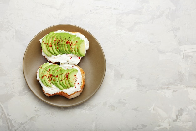 Avocat frais tranché sur deux toasts d'avocat avec du fromage à la crème en sandwich