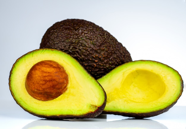 Avocat avec graines isolé sur fond blanc. Source d'oméga 3 provenant de la nourriture naturelle. Des aliments sains pour bébé. Demi morceaux d'avocats disposés avec un beau motif. Aliments biologiques pour végétariens.