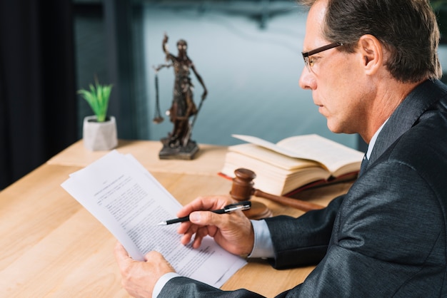 Avocat mâle mature tenant un stylo en main vérifier le document papier dans la salle d&#39;audience