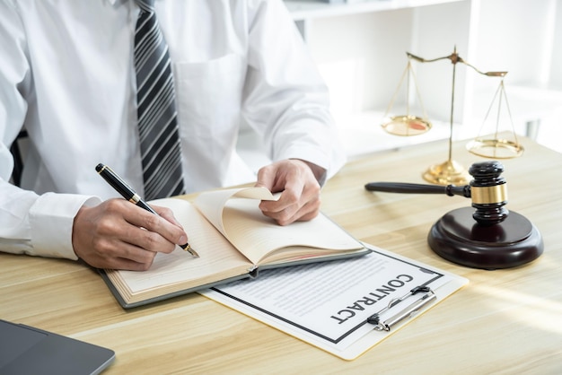 Photo avocat masculin travaillant avec des documents papier de contrat de litige du procès immobilier livres de droit et marteau en bois sur le bureau de la table