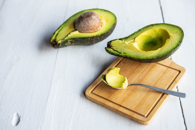 Avocat à moitié coupé sur une table en bois blanc