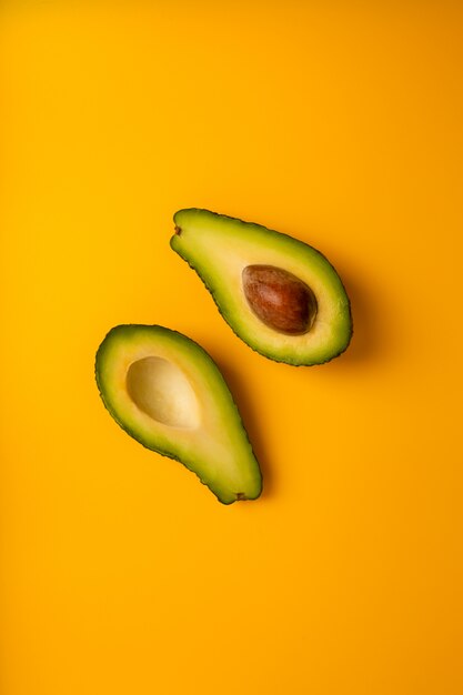 Avocat mûr juteux en deux sur un fond solide jaune avec copie espace. Modèle d'aliments biologiques végétaliens, végétariens, crus. Style Eco détox.