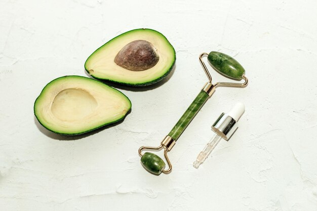 Avocat mûr vert avec gouache de grattoir de jade avec sérum facial sur fond clair