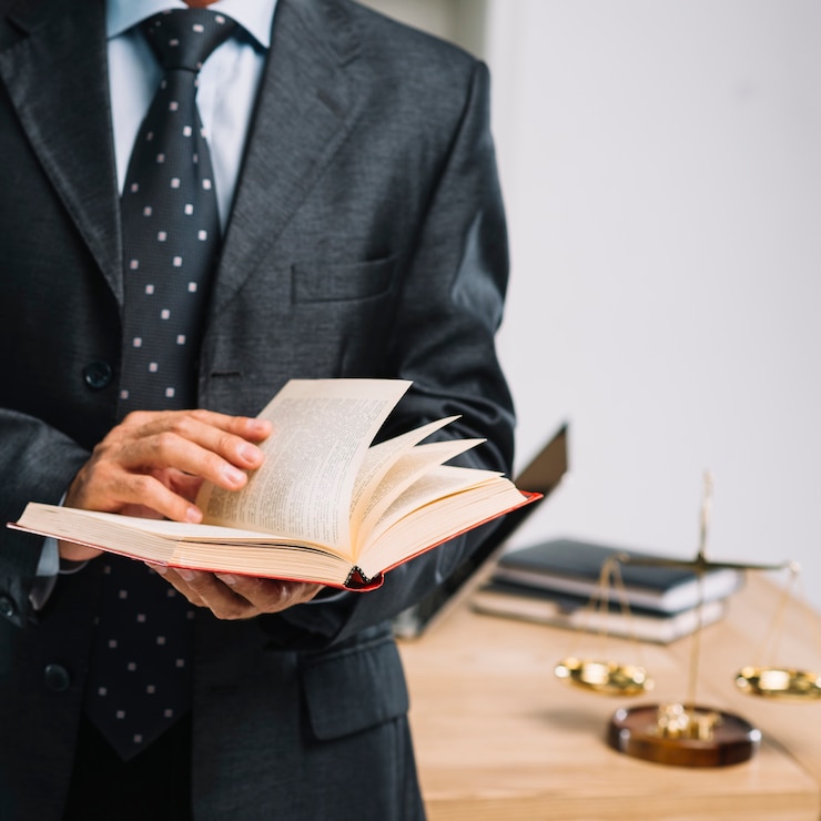 Photo un avocat qui lit un livre devant son bureau.