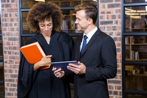 Avocat regardant une tablette numérique et interagissant avec un homme d'affaires au bureau