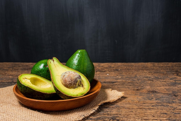 Avocat sur une vieille table en bois Moitiés sur un bol en bois et concept d'aliments sains Fruits