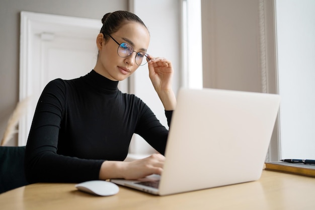 Une avocate utilise un ordinateur portable au bureau et écrit un message à un collègue Lunettes d'ordinateur sur le visage