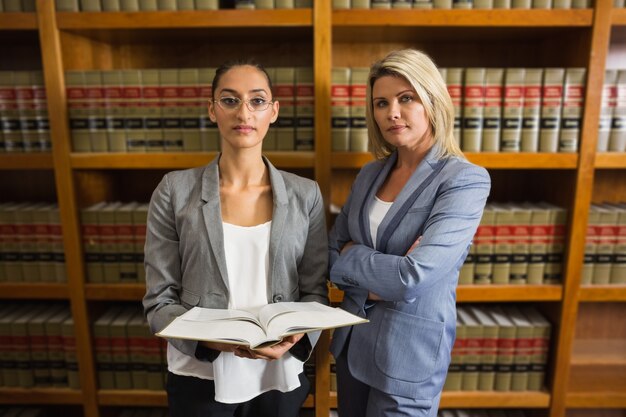 Avocats regardant la caméra dans la bibliothèque de droit