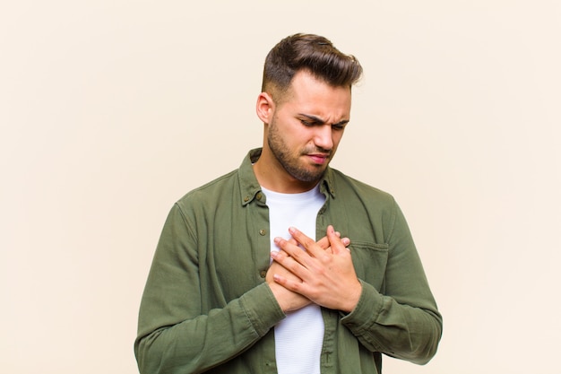 avoir l'air triste, blessé et le cœur brisé, tenir les deux mains près du cœur, pleurer et se sentir déprimé