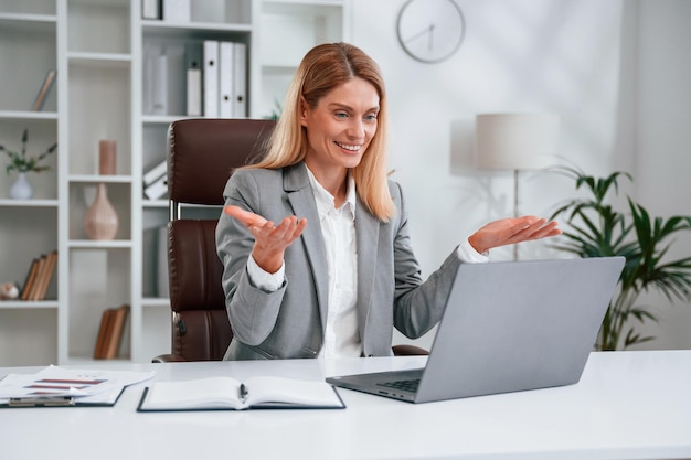 Avoir un appel en ligne femme d'affaires vêtements formels travaille au bureau