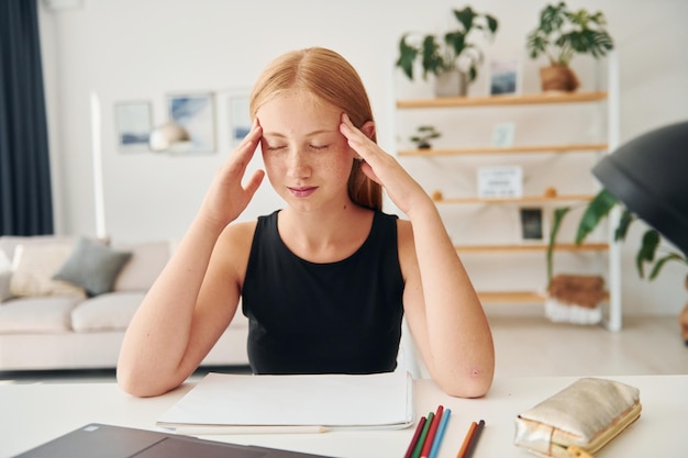 Avoir un mal de tête Une adolescente aux cheveux blonds est à la maison pendant la journée