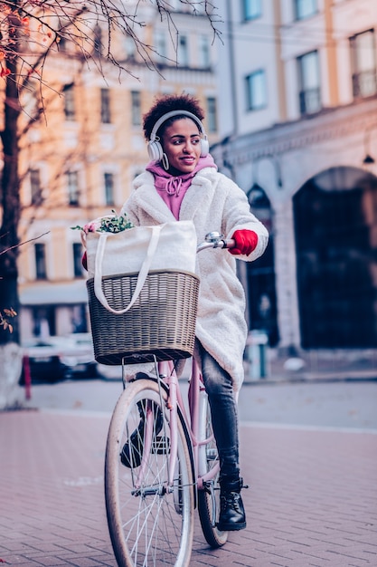 Avoir un rêve. Jolie jeune femme gardant le sourire sur son visage en faisant du vélo