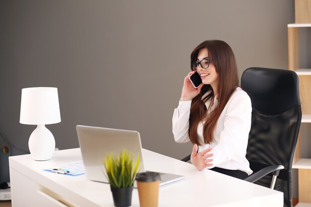 Axé sur le travail. Belle jeune femme à l'aide de son ordinateur portable assis sur une chaise à son lieu de travail.