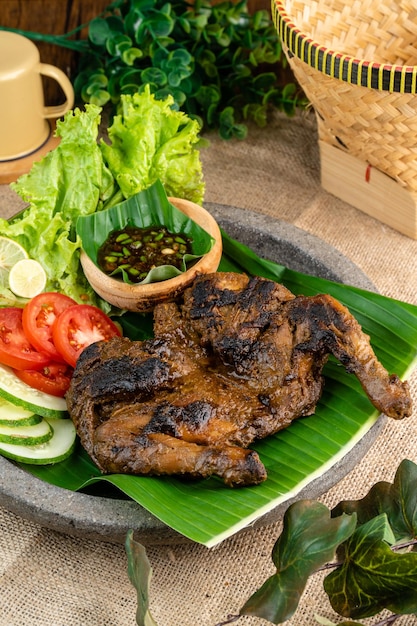 Ayam bakar ou poulet rôti sur une pousse de feuille de bananier sur un fond en bois rustique