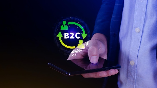 B2C Concept de stratégie de marketing d'entreprise à client L'homme d'affaires utilise un smartphone avec une icône virtuelle B2C pour la communication de la stratégie d'entreprise. Rétroaction marketing en ligne Stratégie de marketing de commerce électronique