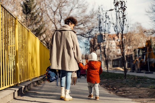 Une baby-sitter ou une soignante qui accompagne un petit garçon à la maternelle pour le premier jour d'école