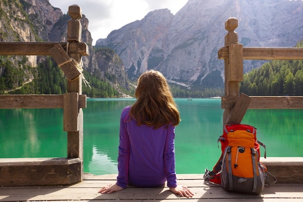 Backpacker fille assise sur une jetée et regardant le lac de Braies, Dolomites Italie