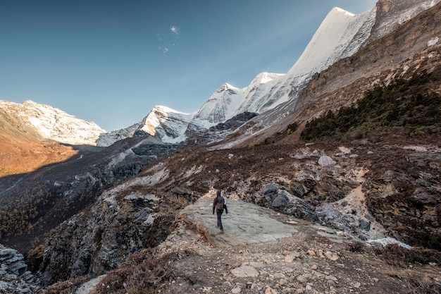 Backpacker homme marchant à la falaise avec la chaîne de montagnes de neige