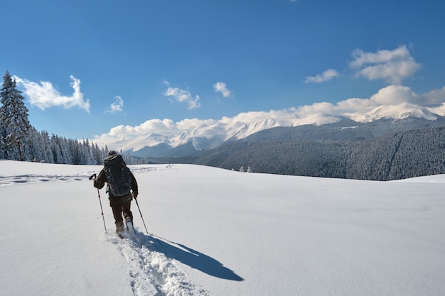 Backpacker de l'homme randonnée à flanc de montagne enneigée par une froide journée d'hiver.