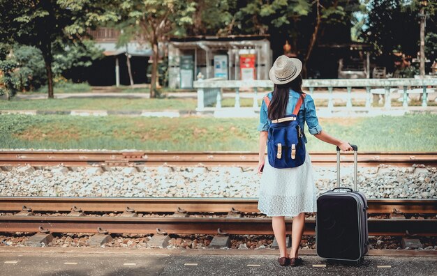 backpacker jeune fille ont des bagages en attente de train à la gare.