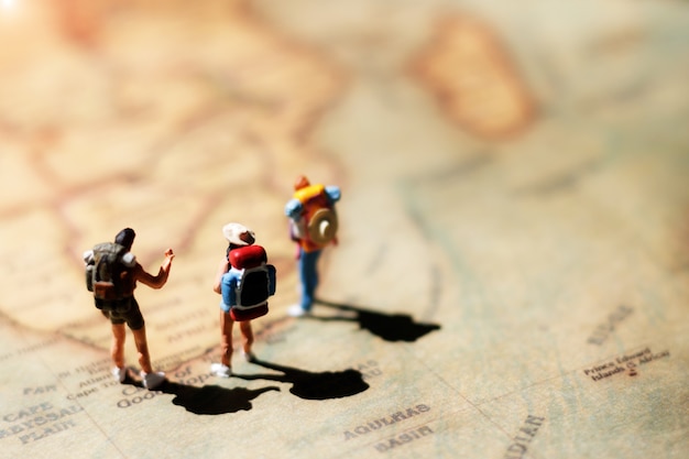 Backpacker miniature debout sur la carte du monde.