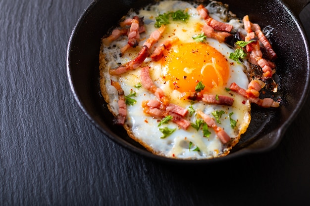 Bacon au fromage et oeuf au plat dans une poêle en fonte avec espace pour copie