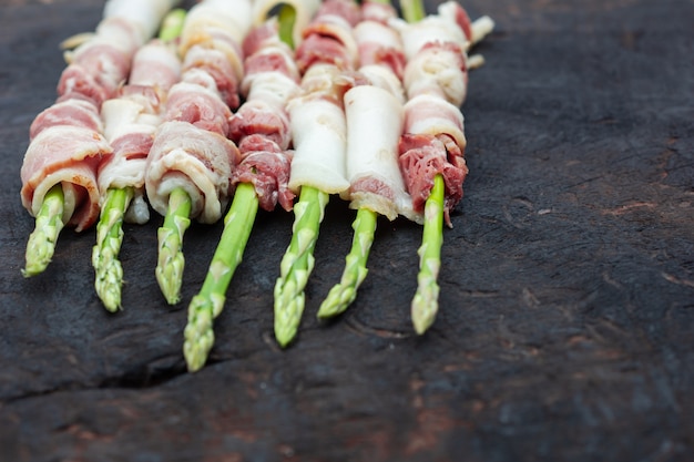 Photo bacon enveloppé d'asperges sur fond de bois