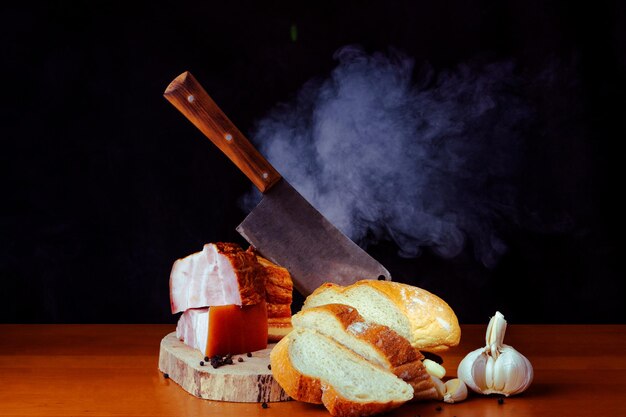 Bacon avec de la viande avec un couteau sur la planche à découper en bois avec un fond noir