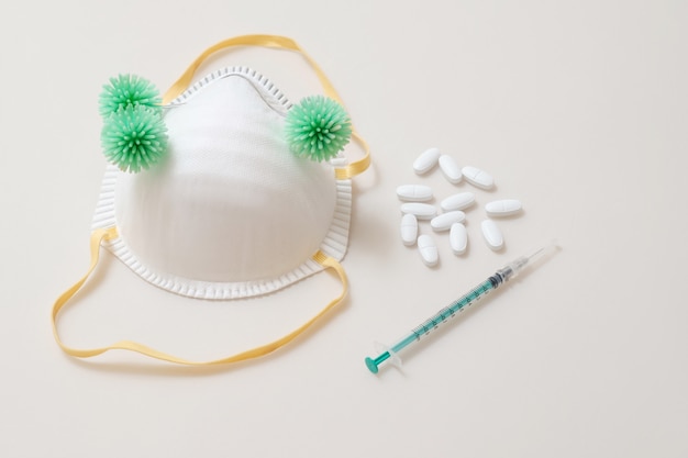 Bactéries virales sur masque médical avec des seringues et des comprimés de pilles sur la table