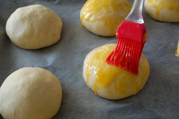 Badigeonner l'oeuf sur la pâte à gâteau crue en appliquant le jaune d'oeuf sur la pâte crue