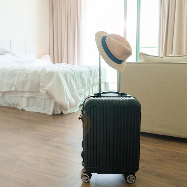 Bagages noirs avec chapeau dans une chambre d'hôtel moderne après l'ouverture de la porte Bagages pour le temps de voyager service voyage voyage vacances d'été et concepts de vacances