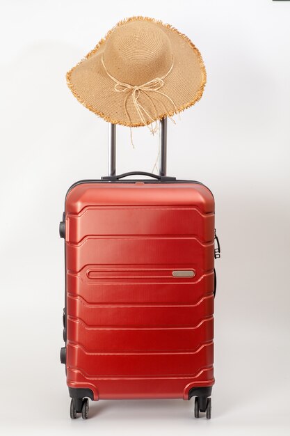 bagages rouges avec chapeau de paille