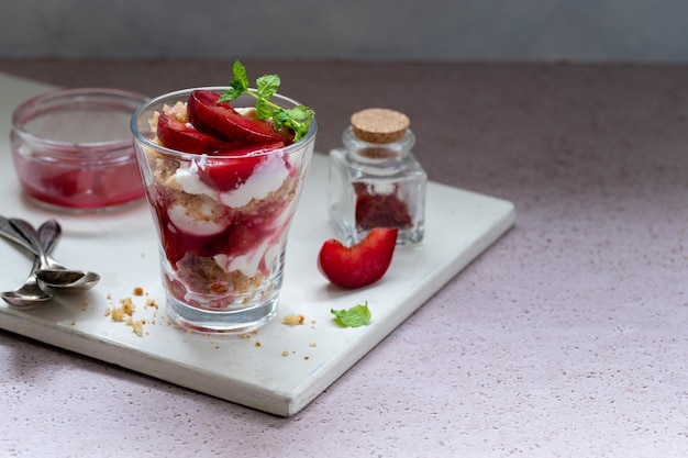 Bagatelles en couches avec prunes rouges et crème fouettée dans des verres à dessert